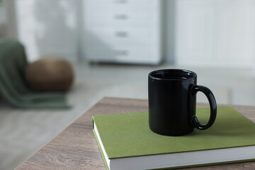 Wall Mural - Ceramic mug of tea and book on wooden table. Mockup for design