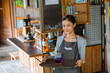 © Odua Images - female barista in apron standing bring the tray with the drinks over it