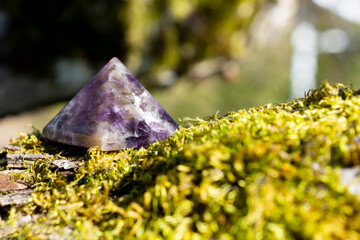 Wall Mural - A close up image of a amethyst crystal pyramid on a thick green patch of moss.