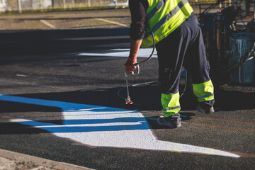 Process of making new road surface markings with a line striping machine, workers improve city infrastructure, demarcation marking of pedestrian crossing with a hot melted paint on asphalt pavement