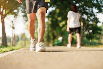 Wall Mural - man jogging and walking on the road at morning with Energy Drink water, adult male in sport shoes running in the park outside. Exercise, wellness, healthy lifestyle and wellbeing concepts