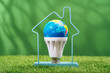 Globe in LED light bulb inside house frame on green grass background. Green energy efficient saving and smart house solutions. Sustainable consumption and lifestyle. Earth Day. Forest