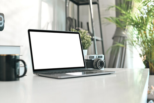 Creative designer workplace with laptop computer, retro camera and coffee cup on white table