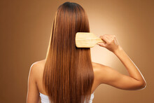 Back Of Hair, Brush And Woman In Studio For Beauty, Wellness And Keratin Treatment On Brown Background. Hairdresser Mockup, Salon And Girl Brushing Hairstyle For Growth, Haircare Texture Or Cosmetics