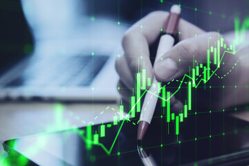 Aufkleber - Close up of hand using digital tablet with pen and growing green candlestick chart on blurry desktop background. Forex, trade and finance concept. Double exposure.