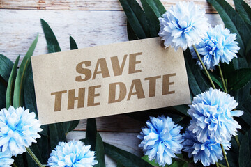  Save the Date text message with flower decoration on wooden background