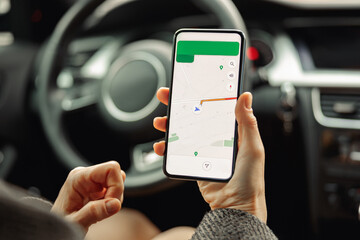 closeup of female driver using cell phone with gps navigation app on screen while sitting in car