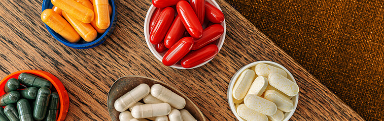 pills banner top view. multivitamin dietary supplements on a wooden desk. mental wellbeing and personal health concept