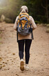 Girl hiking, back view or woman in nature, forest or wilderness for a trekking adventure. Freedom, backpack healthy female hiker walking in a natural park or woods for exercise or wellness on holiday