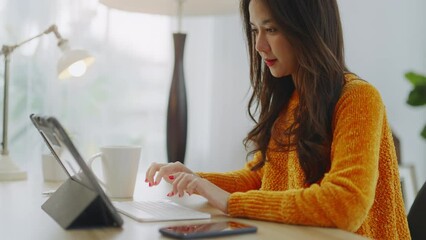 Wall Mural - Smiling Asian freelance business women casual wear sitting on sofa using laptop looking at screen typing message,working call video conference in living room.Happy young girl relax at home in summer