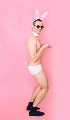 Wall Mural - Full body portrait of sexy playful cheerful man wearing fluffy ears having fun isolated over pink pastel color background.