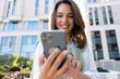 © opolja - Young business woman wearing professional look smiling confident at the city using smartphone.