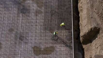 Wall Mural - Workers in yellow uniform lay metal bars on the rebars floor