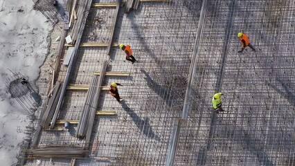 Wall Mural - Workers carrying metal bars stepping on reinforcement rebars above slab floor