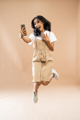 excited asian woman in casual clothes jumping while looking at the phone on isolated background