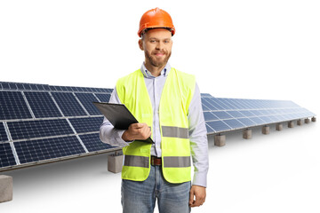 Wall Mural - Male engineer with a hardhat holding a clipboard in front of photovoltaic power station