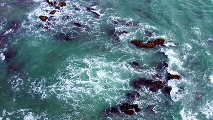 Wall Mural - Aerial view from above of the sea waves at the rocky shore. Ocean coast. Calm beautiful video on the background for tourism, design and advertising