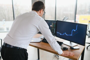 Successful trader in formalwear checking cryptocurrency information data on finance market graph, working in office