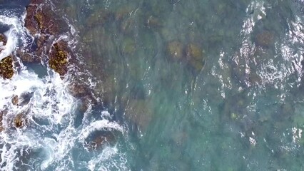 Wall Mural - Aerial view from above of the sea waves at the rocky shore. Ocean coast. Calm beautiful video on the background for tourism, design and advertising