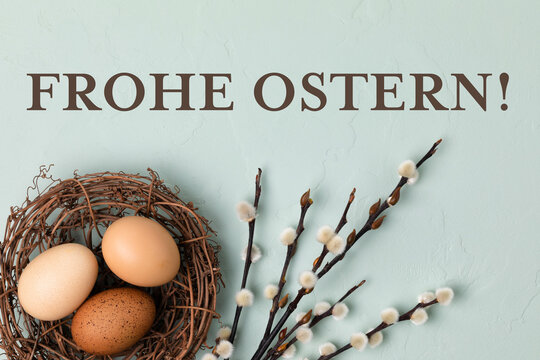Fototapete - Happy Easter Card -  German text. Rustic nest with brown Easter eggs and branches of pussy willow on light blue background. Flat lay, top view
