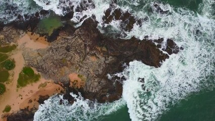 Wall Mural - Aerial view from above of the sea waves at the rocky shore. Ocean coast. Calm beautiful video on the background for tourism, design and advertising