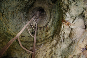 Wall Mural - View from inside vertical stone tube downcast shaft with ladder