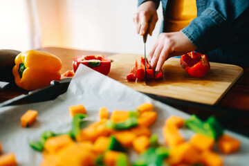 Wall Mural - Chef hands cutting vegetables mix for roasted vegetarian recipe - Vegan healthy food cooked on oven tray - Focus on hand holding pepper