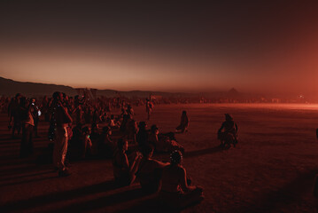 Wall Mural - People walking towards sunset at a festival in the desert. Beautiful music festival in a desert.