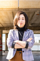 Portrait of female entrepreneur in formal suit with crossed arms outdoors. Young woman in formal wear arms crossed outdoors