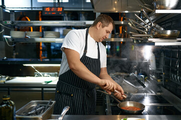 Chef adding pepper to sauce with tomato for pasta