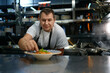 © Nomad_Soul - Portrait of satisfied chef placing basil leaf in plate with pasta