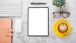 © Satori Studio - Modern office desk workplace with blank screen tablet, keyboard, mouse,noebook, pen, eyeglass and cup of coffee, Top view flat lay with copy space.