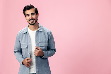 Poster - Portrait of a stylish brunette man with a beard beautiful smile on a pink background in a white T-shirt and jeans smile and joyful emotion on his face, copy space