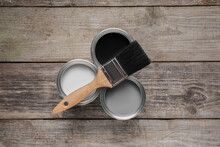 Cans Of White, Black And Grey Paints With Brush On Wooden Table, Flat Lay