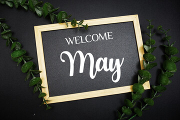 Canvas Print - Welcome May text message on wooden blackboard with green leaf decoration