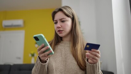 Wall Mural - Young blonde woman using smartphone and credit card sitting on floor at home