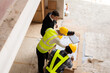 © ArLawKa - Three colleagues discussing data work and tablet Laptop with architecture project at construction site Architect team working on blueprints for architectural plans construction project engineer