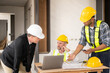 © ArLawKa - Three colleagues discussing data work and tablet Laptop with architecture project at construction site Architect team working on blueprints for architectural plans construction project engineer