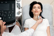 © wedmoments.stock - Ultrasound diagnosis of the thyroid gland of a young woman in the clinic. A female doctor holds an ultrasound probe along the patient's neck. Health concept.