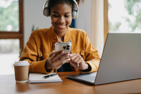 Woman using smart phone for mobile payments online shopping,omni channel,sitting on table,virtual icons graphics interface screen in morning light