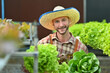 © Prathankarnpap - Happy male organic farmer holding a wooden crate with fresh organic vegetables sitting in greenhouse plantation