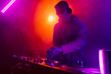 Male DJ Playing Music In The Night Club
