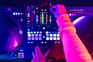 Wall Mural - Hands of a DJ creating and regulating music on dj console mixer at club concert