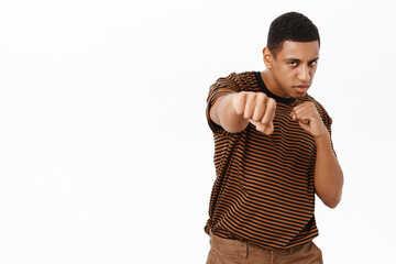 Wall Mural - Portrait of strong african american man makes punch, standing in boxing pose, white background