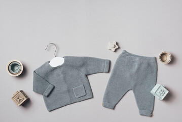 Baby stuff and accessories. Knitted clothes - cardigan, pants, shoes, toys and cubes. Baby shower concept. Flat lay, top view. Copy space