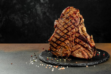 Wall Mural - T-bone grilled beef steak with spices on a dark background. Restaurant menu, dieting, cookbook recipe