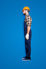 Wall Mural - Full size fullbody snap, profile portrait with legs of virile harsh repairer in shirt and overall isolated on grey background