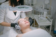 © Anna - Cosmetologist and dermatologist cleans the face of a lying woman patient in a beauty salon. Young woman on a cosmetology procedure for facial skin care