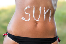Woman Applying Sun Cream On Tanned Stomach. Sun Protection.Sun Cream. Skin And Body Care. Girl Using Sunscreen To Skin.
