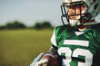 © Flamingo Images - Football player holding a ball at practice